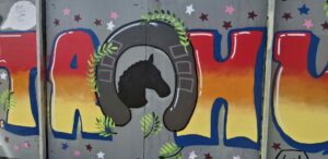 Puna-oranssi graffiti seinällä jossa lukee TAHU, keskellä Varsapuiston koulun logo